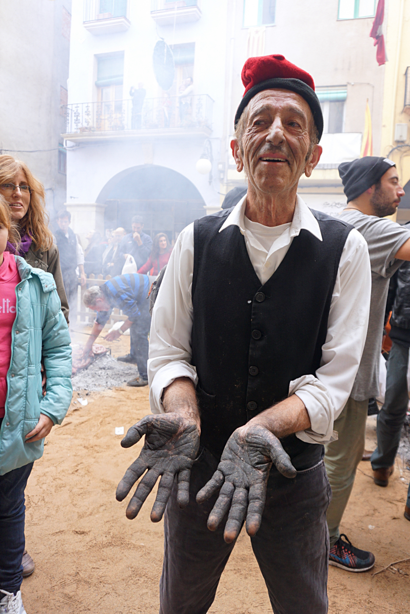 A local man cooking calçots shows his black hands to show how dirty cooking the calçots is in the town of Valls during the Fiesta de la Calçotada de Valls in 2016.